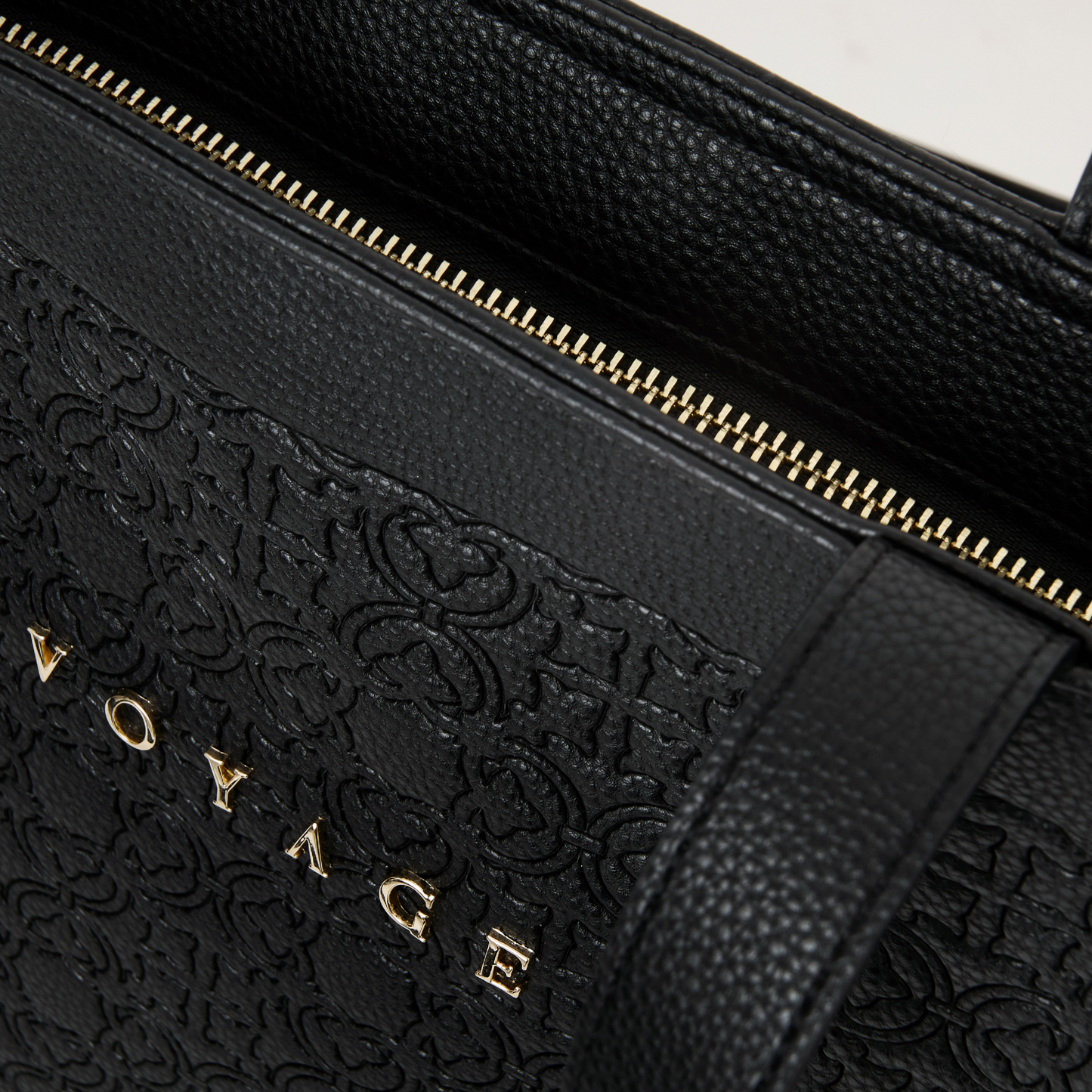 Close-up van de rits van een chique leren tas. De rits is goud en het materiaal heeft een leer-look en feel en is zwart.